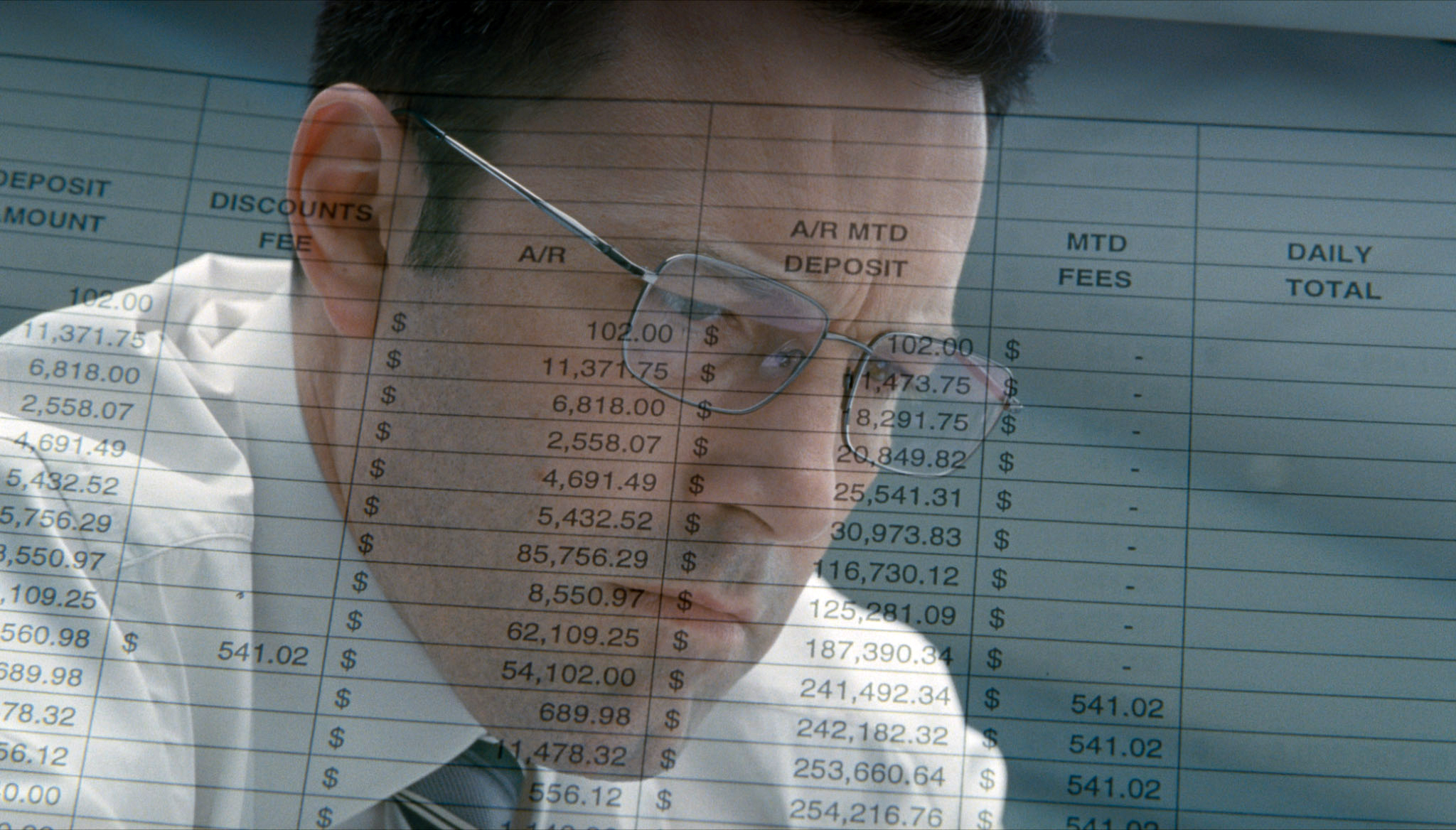 Ben Affleck looking down with numbers and spreadsheets on paper transposed over his face in The Accountant