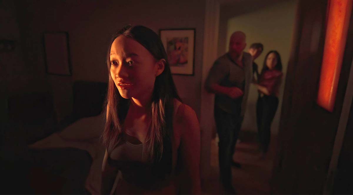 A woman standing in a room with three other people standing by a nearby door in Presence