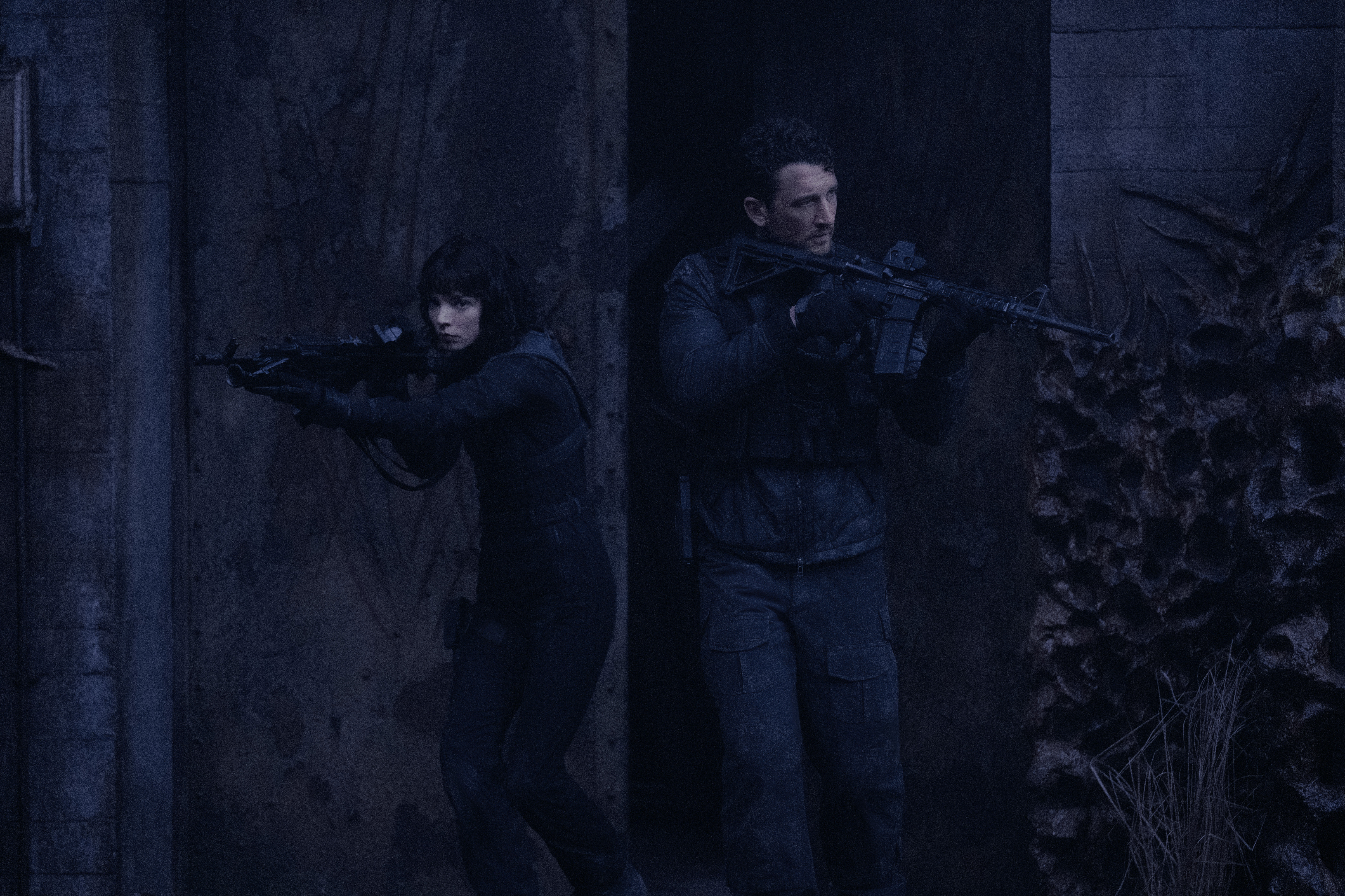 Anya Taylor-Joy and Miles Teller holding rifles in black tactical gear in The Gorge