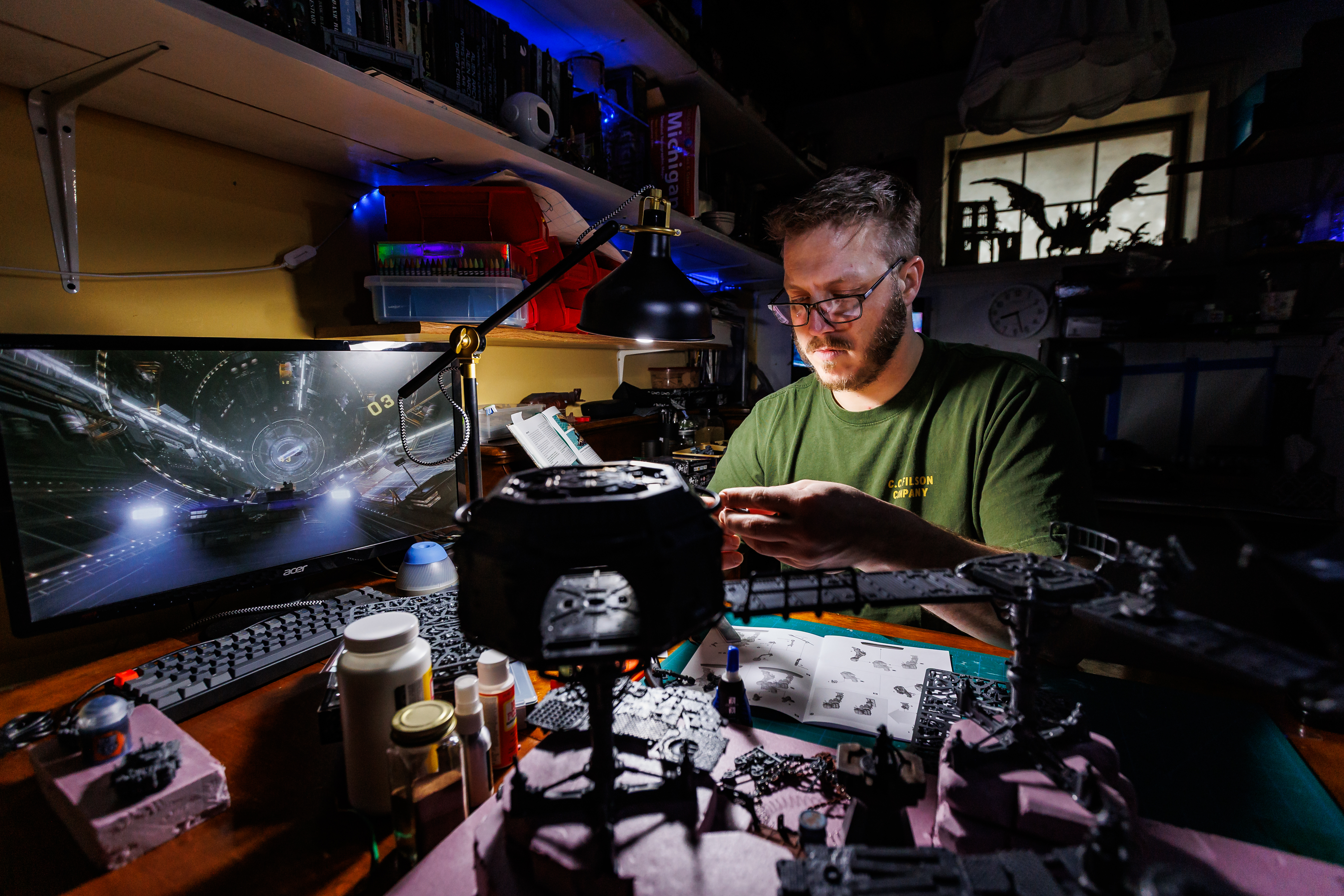 The author working on a diorama of Warhammer miniatures inside a dimly lit space.