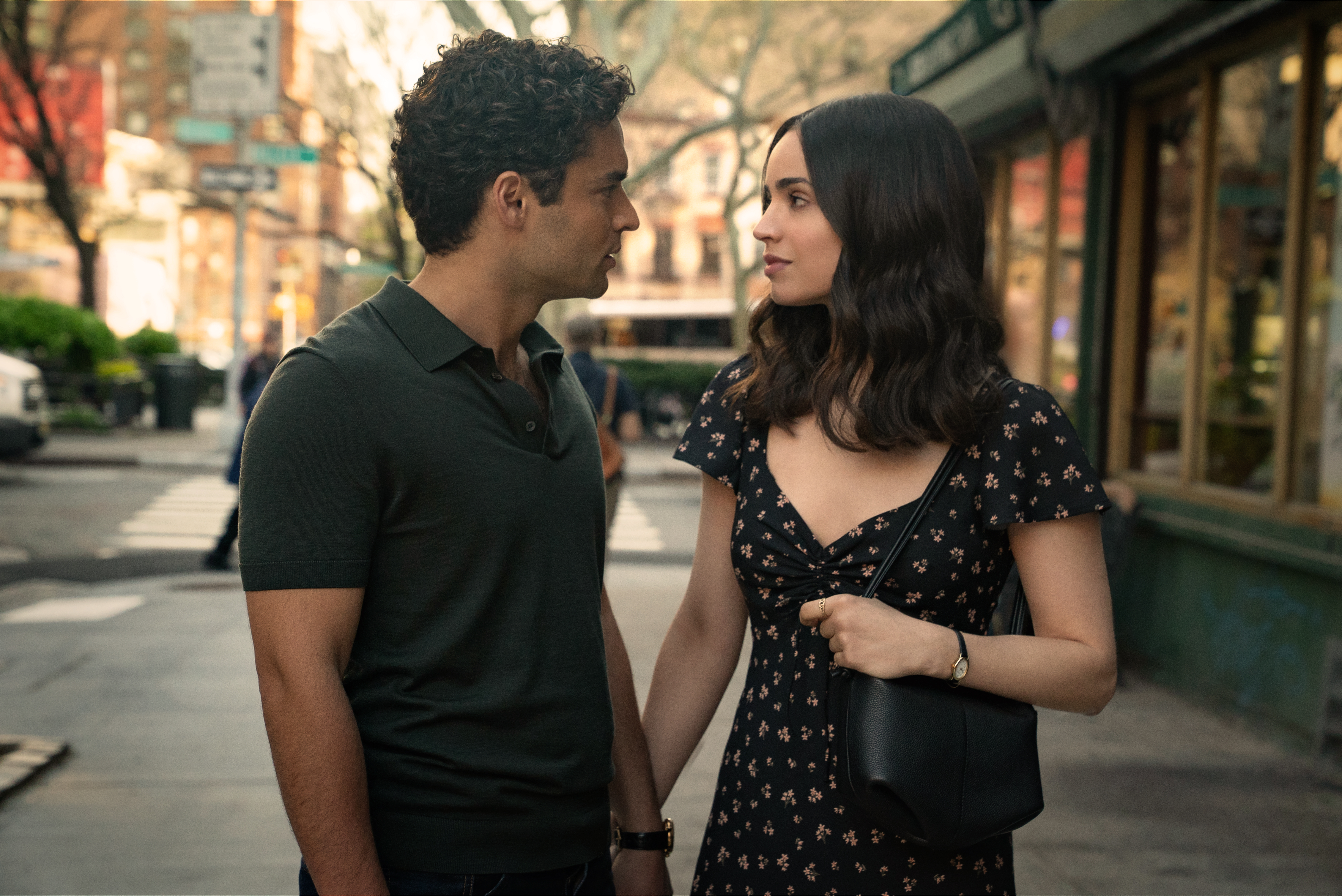 A man and a woman holding hands while walking down a street in The Life List.
