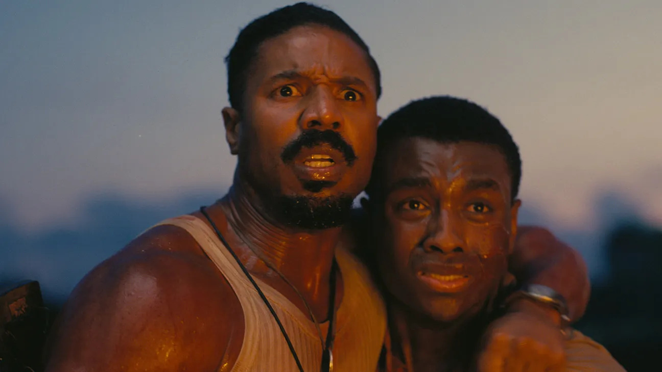 Michael B. Jordan and another man staring off in terror at a fiery sight in Sinners