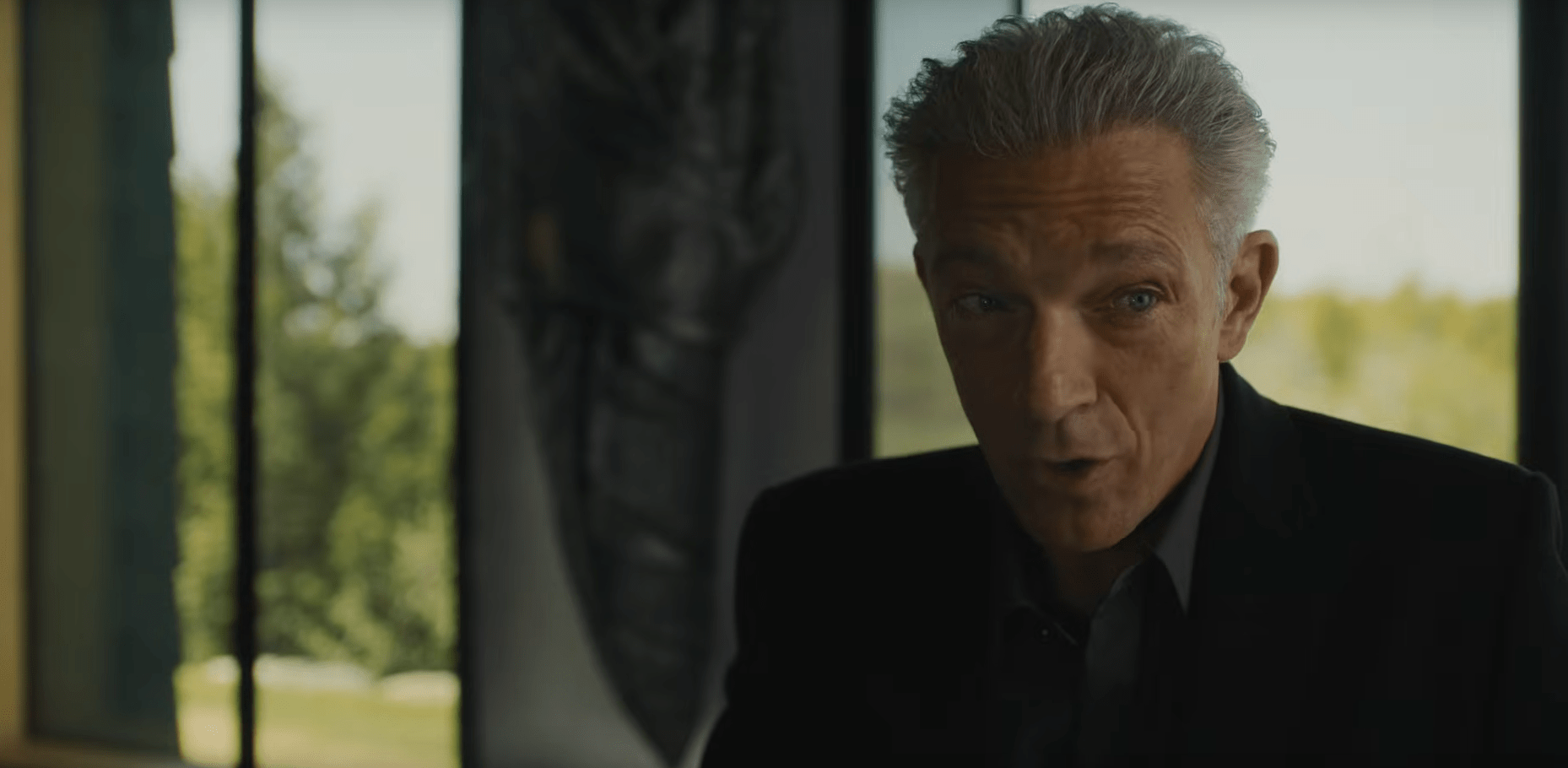 Vincent Cassel sits at a fancy restaurant wearing all black in The Shrouds