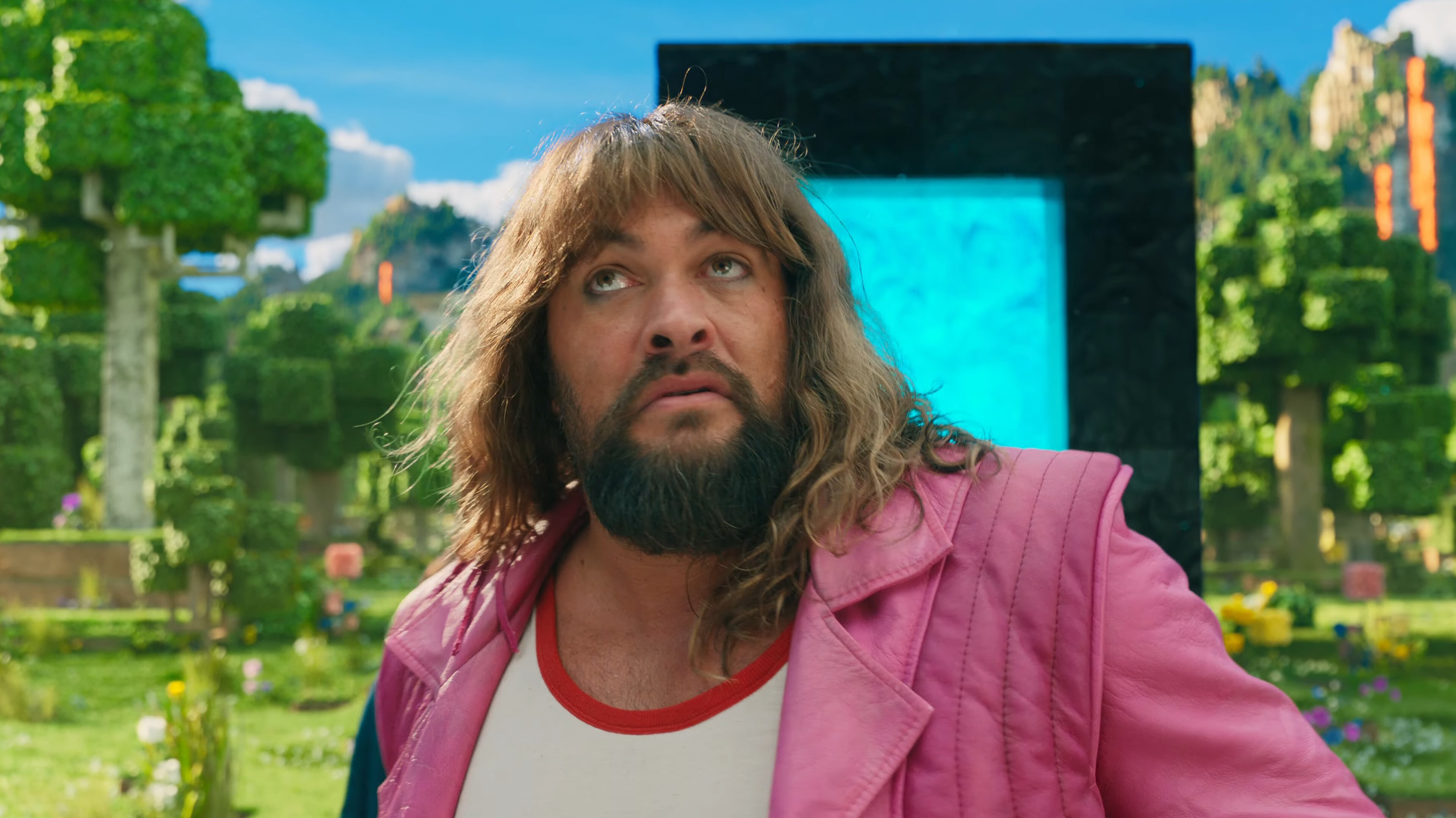 Jason Momoa with a long mullet dressed in a pink leather jacket in A Minecraft Movie