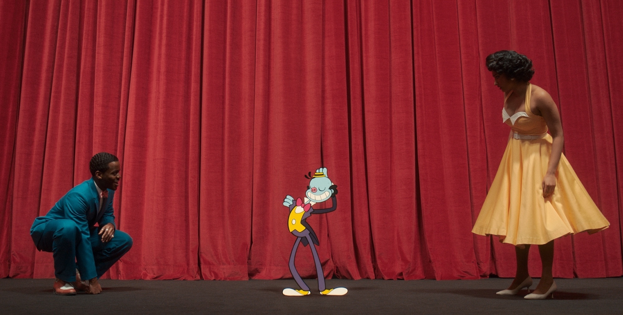 in a scene from Doctor Who, Mr. Ring-a-Ding preens on the curtained proscenium of a movie theater, while the Doctor and Belinda look at him in curiosity.