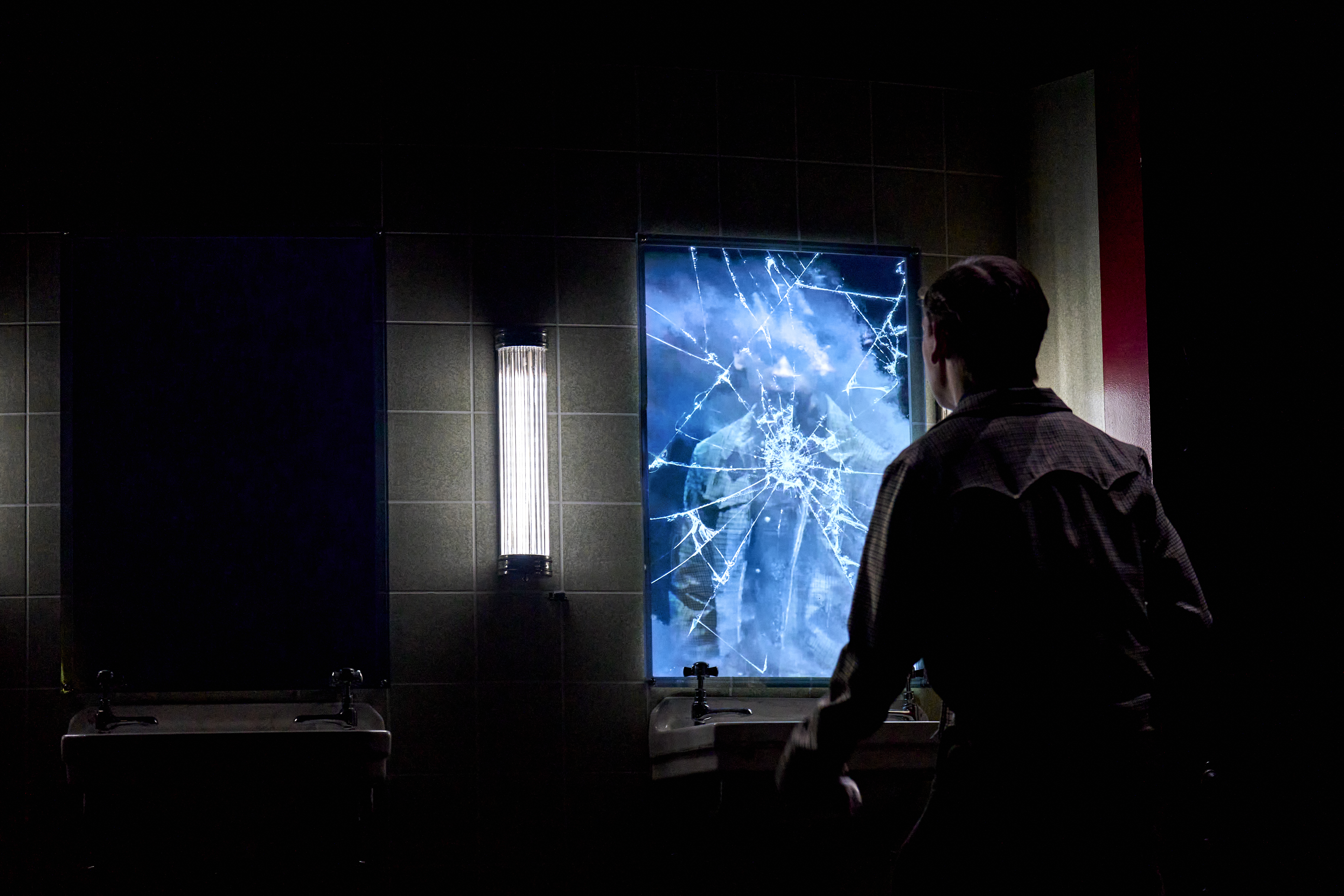 Henry looking at the mirror and seeing it cracked in a still from Stranger Things: The First Shadow