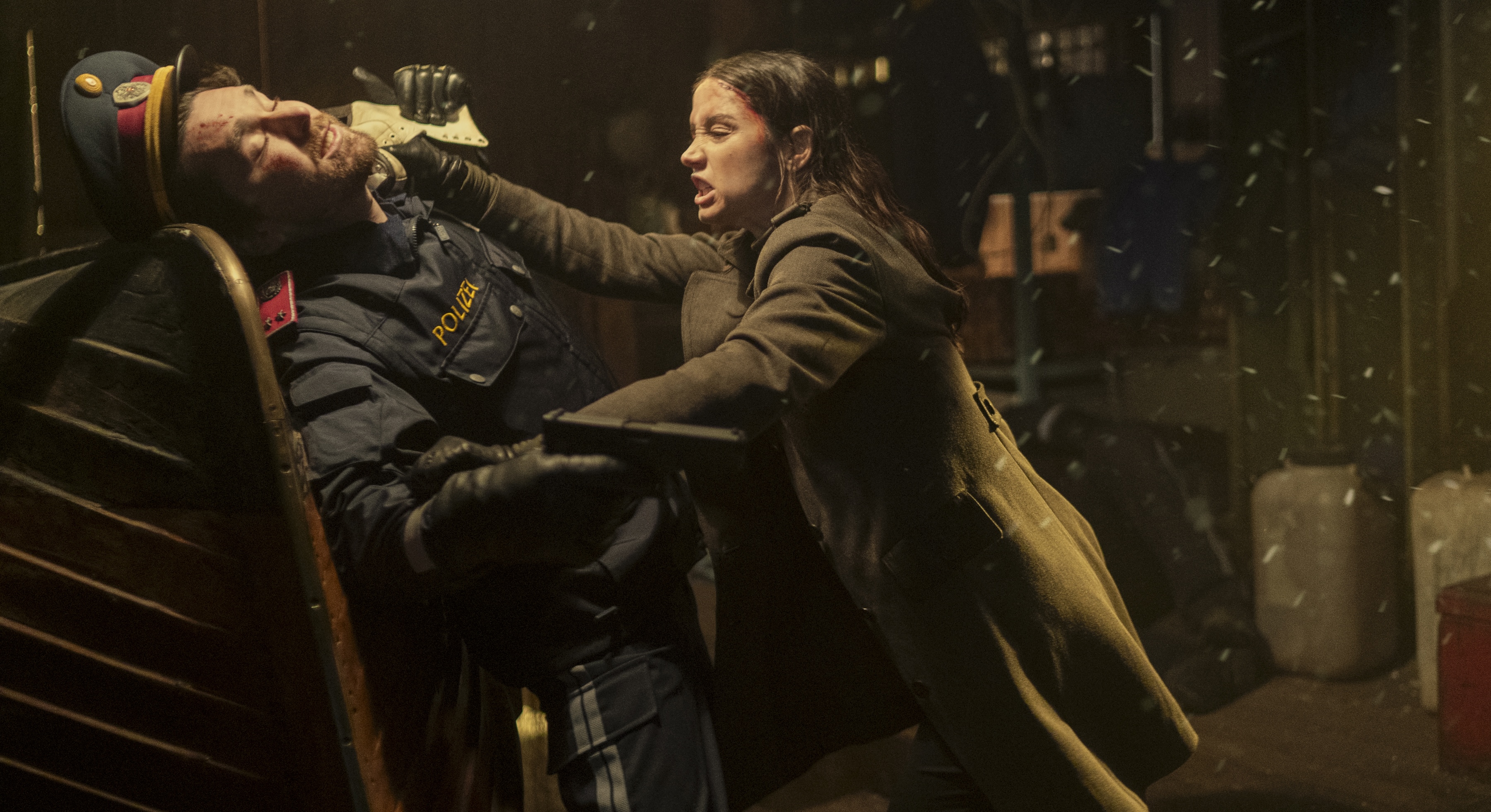 Eve (Ana de Armas) strangles a gun-wielding man in a retro military hat and trenchcoat in the John Wick spin-off Ballerina