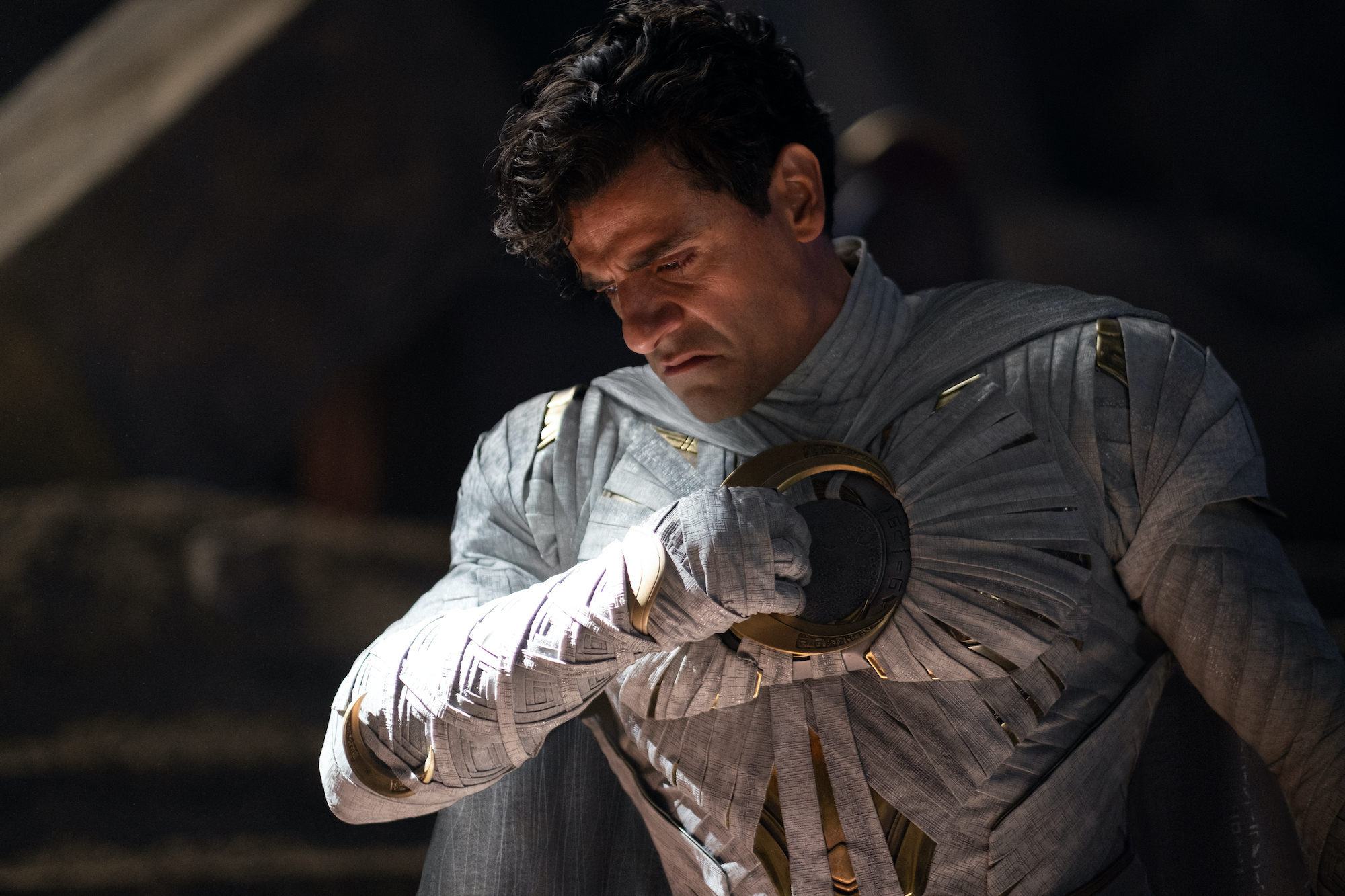 Marc Spector unmasked in the Moon Knight costume, pulling a crescent blade from his chest.